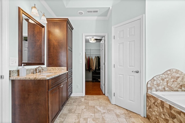 bathroom with vanity, visible vents, ornamental molding, stone finish floor, and a walk in closet