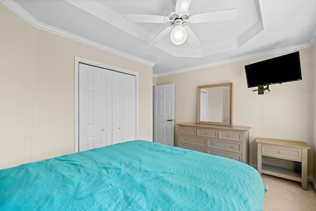 bedroom featuring ornamental molding, a tray ceiling, a closet, and light colored carpet