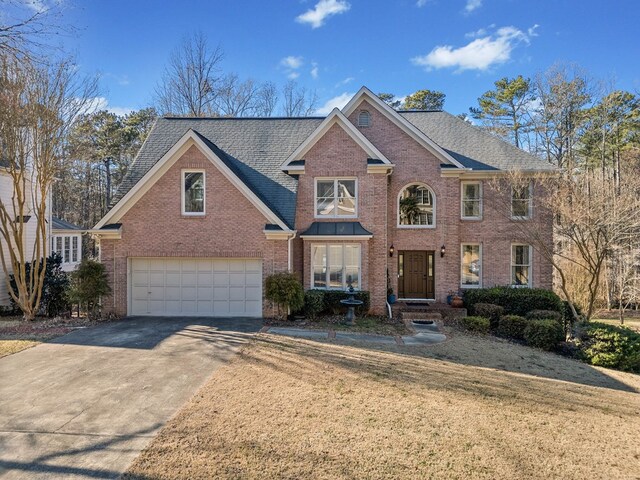 view of front of property with a garage, brick siding, concrete driveway, roof with shingles, and a front yard