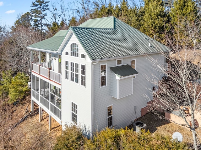 view of property exterior featuring a sunroom, a balcony, and central air condition unit