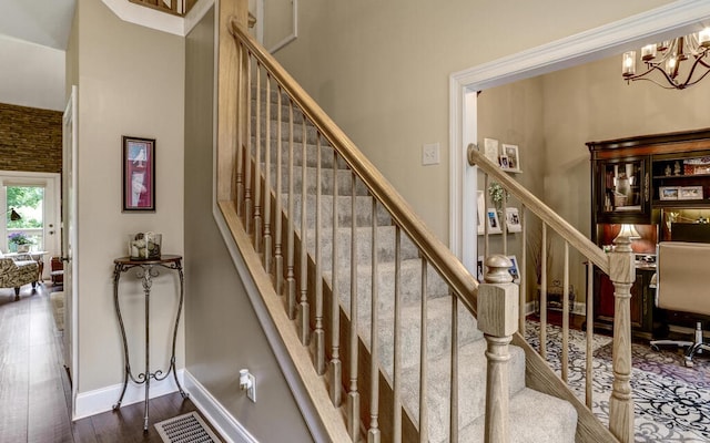 stairs with a towering ceiling, hardwood / wood-style floors, and a chandelier