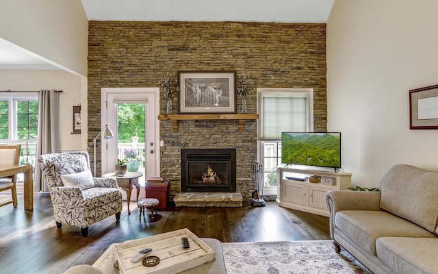 living room with a stone fireplace, dark hardwood / wood-style floors, and a healthy amount of sunlight