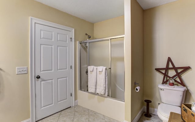 bathroom with toilet, tile patterned flooring, and bath / shower combo with glass door