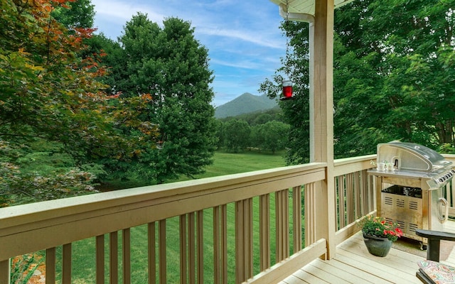 wooden deck featuring a mountain view and a lawn