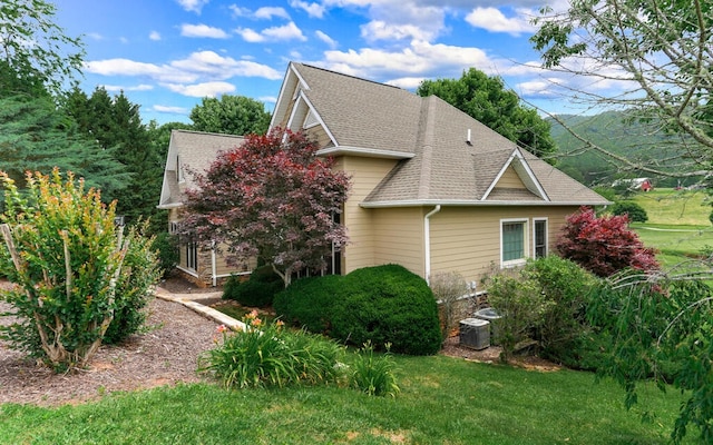 view of side of home with central air condition unit and a lawn