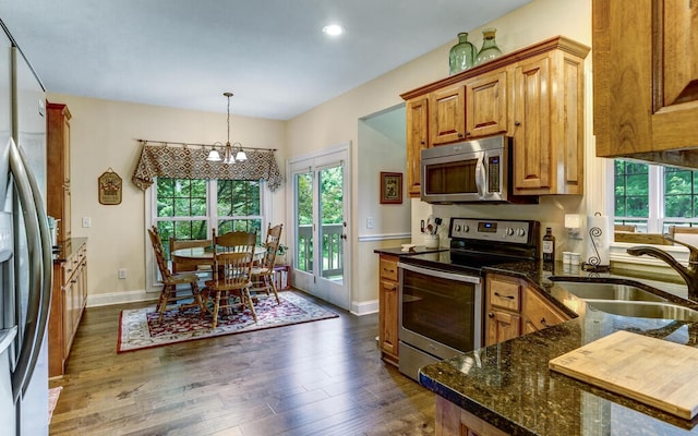 kitchen featuring sink, dark hardwood / wood-style flooring, hanging light fixtures, stainless steel appliances, and a notable chandelier