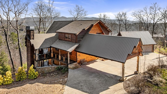 view of front of property with metal roof, concrete driveway, a chimney, and a garage