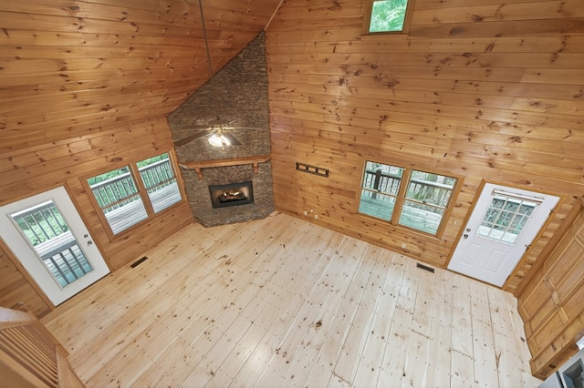 776 Mountain Oak Rd, Ellijay, GA 30536 - unfurnished living room with high vaulted ceiling, wooden walls, a stone fireplace, a ceiling fan, and light wood-type flooring