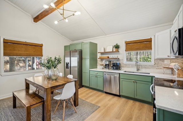 kitchen featuring appliances with stainless steel finishes, a sink, lofted ceiling with beams, and green cabinets