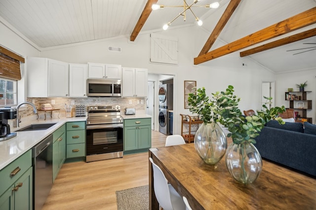 kitchen featuring visible vents, stacked washer / dryer, appliances with stainless steel finishes, green cabinets, and a sink