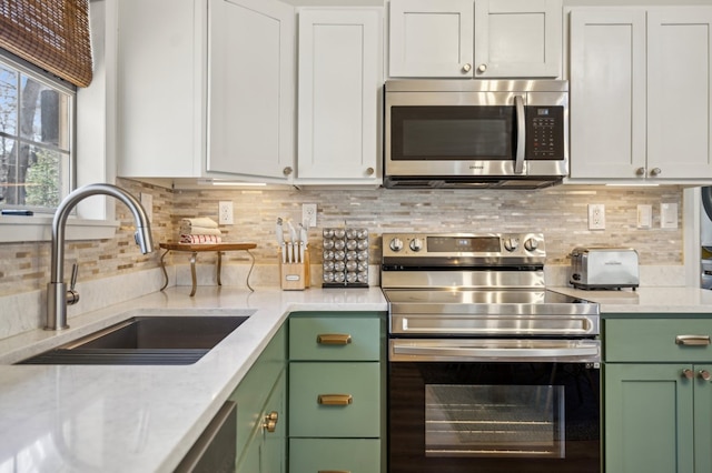 kitchen featuring green cabinets, stainless steel appliances, backsplash, and a sink