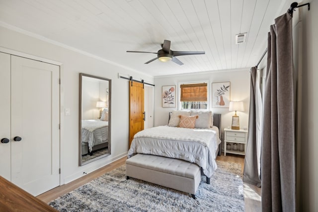 bedroom with visible vents, a barn door, ornamental molding, wood ceiling, and wood finished floors