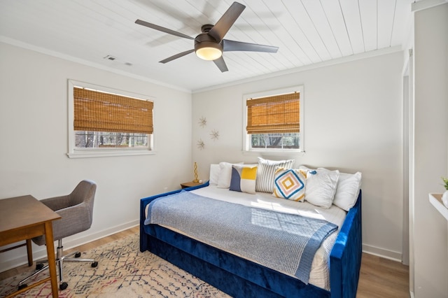 bedroom featuring ornamental molding, visible vents, baseboards, and wood finished floors