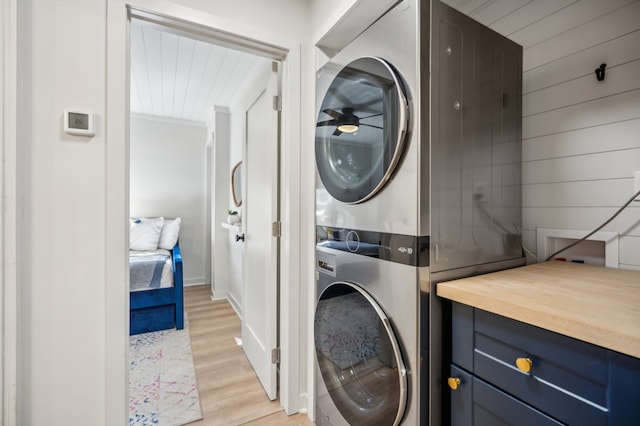 laundry area featuring light wood-style flooring and stacked washer / drying machine