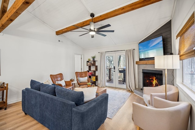 living area with lofted ceiling with beams, french doors, light wood finished floors, and a fireplace