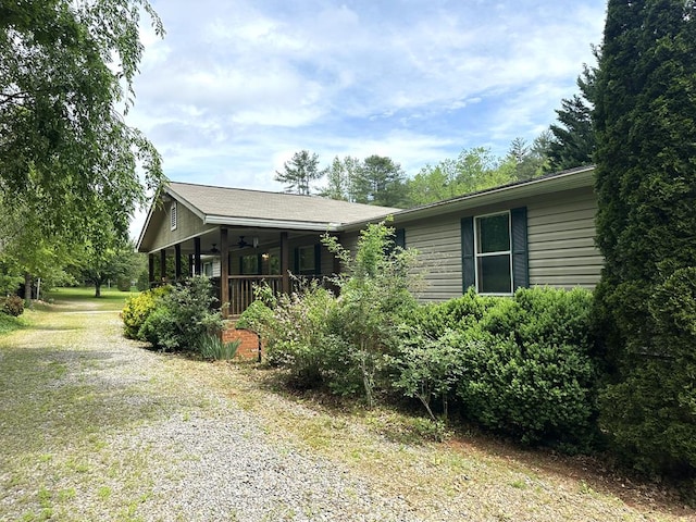 view of front of home with a porch, ceiling fan, and gravel driveway