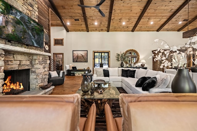 living room featuring hardwood / wood-style floors, beam ceiling, a stone fireplace, and wooden ceiling