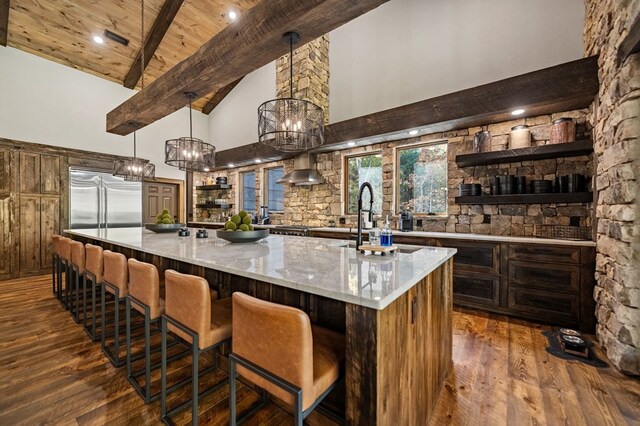 bar with light stone countertops, dark hardwood / wood-style floors, high vaulted ceiling, and built in fridge