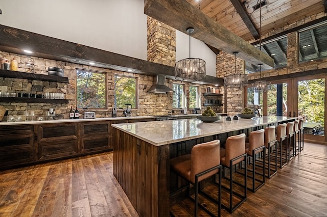 bar with a wealth of natural light, beamed ceiling, and wall chimney range hood