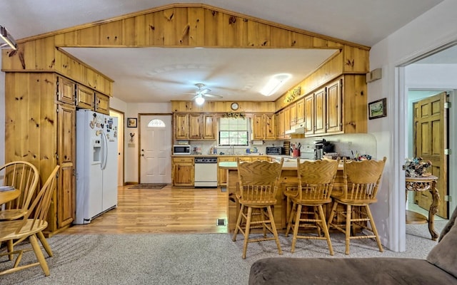 kitchen with lofted ceiling, white appliances, ceiling fan, kitchen peninsula, and a breakfast bar area