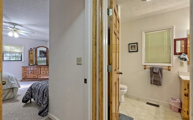 bathroom featuring ceiling fan, vanity, a textured ceiling, and toilet