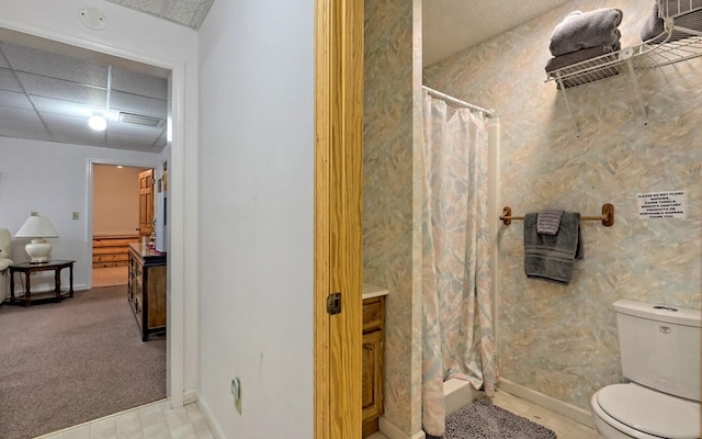 bathroom featuring a drop ceiling, a shower with shower curtain, and toilet