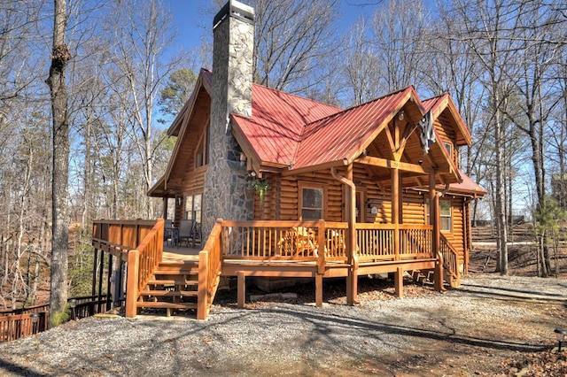 exterior space featuring a chimney, log siding, metal roof, and a wooden deck