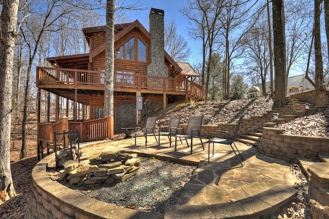 rear view of house with a chimney, stairway, a patio area, a deck, and a fire pit