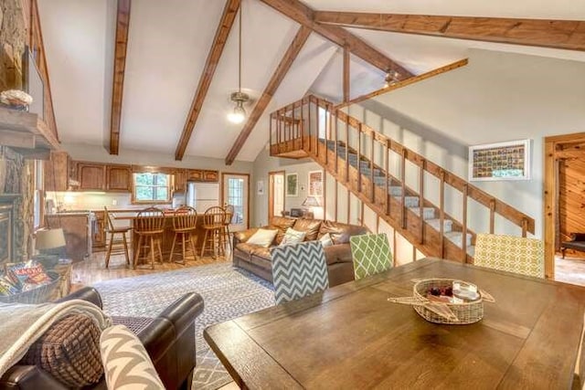 dining space featuring beamed ceiling, a fireplace, and high vaulted ceiling