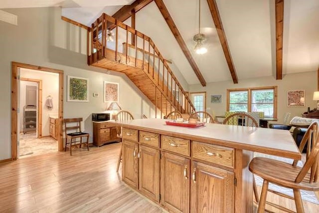 kitchen featuring beam ceiling, light hardwood / wood-style flooring, and high vaulted ceiling