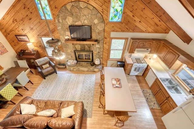 living room with high vaulted ceiling, beam ceiling, light hardwood / wood-style flooring, and a fireplace