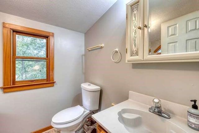 bathroom with a textured ceiling, vanity, and toilet