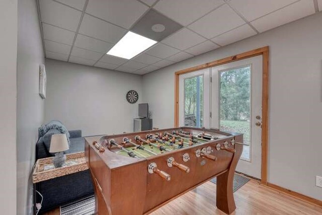 recreation room featuring light hardwood / wood-style floors and a paneled ceiling