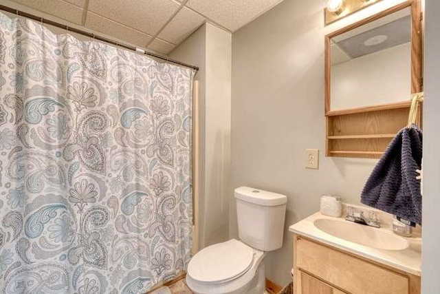 bathroom featuring walk in shower, a paneled ceiling, vanity, and toilet