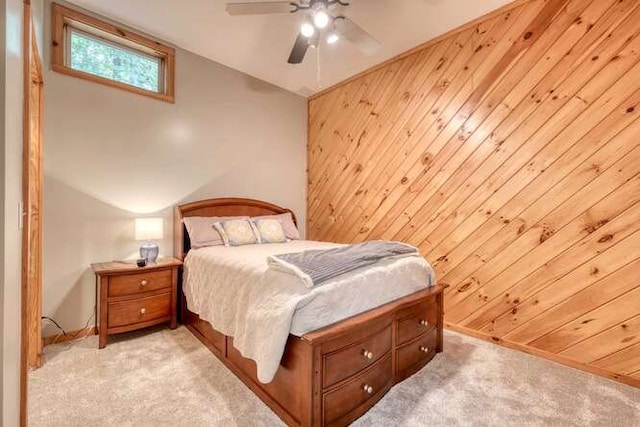 carpeted bedroom featuring ceiling fan, wooden walls, and vaulted ceiling