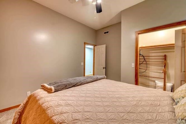 carpeted bedroom with ceiling fan, a closet, and vaulted ceiling