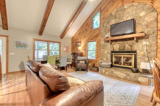 living room featuring light wood-type flooring, a fireplace, beam ceiling, and high vaulted ceiling