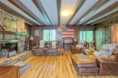 living room featuring beamed ceiling, light hardwood / wood-style flooring, and wooden walls