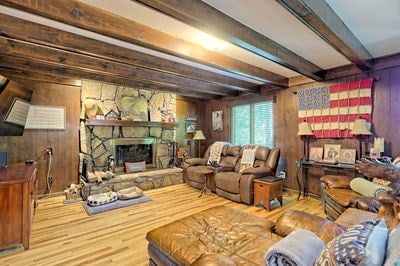 living room featuring beamed ceiling, light hardwood / wood-style floors, and wooden walls