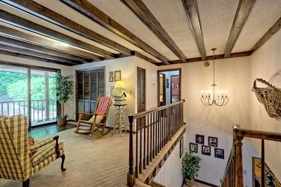 living area featuring beam ceiling, carpet floors, and a notable chandelier