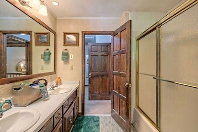 bathroom with vanity, shower / bath combination with glass door, and crown molding