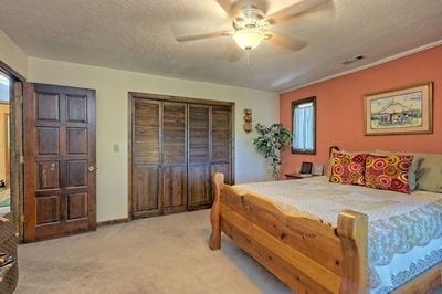 bedroom featuring ceiling fan, light colored carpet, and a textured ceiling