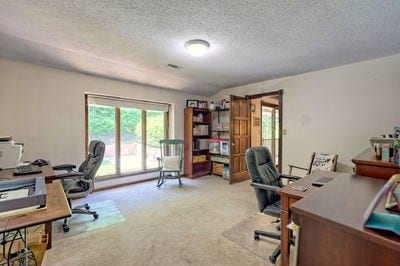 carpeted home office featuring a textured ceiling