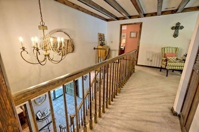 corridor with beamed ceiling, carpet, and a chandelier