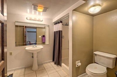 bathroom featuring tile patterned flooring, toilet, and walk in shower