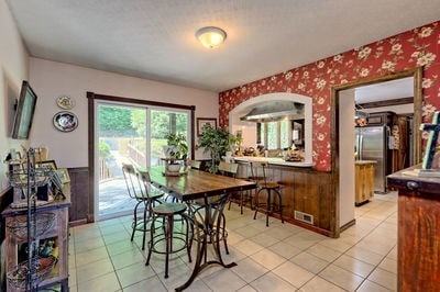 dining space with wooden walls and light tile patterned flooring