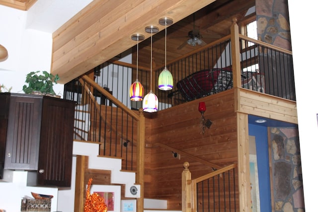 stairs with beam ceiling, wooden walls, high vaulted ceiling, and ceiling fan