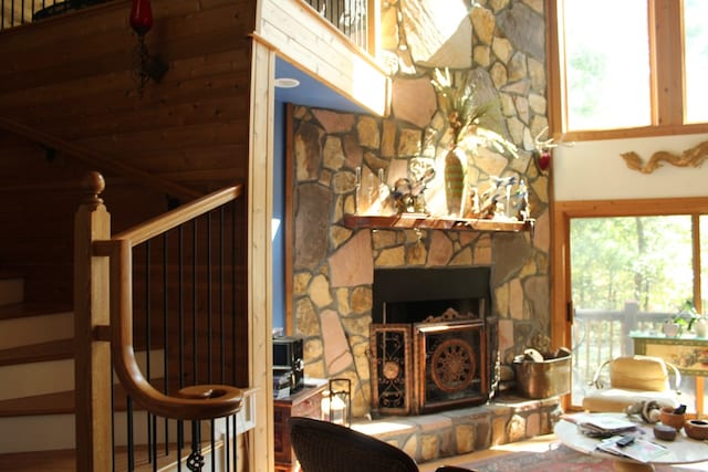 living room with a stone fireplace, a towering ceiling, and plenty of natural light