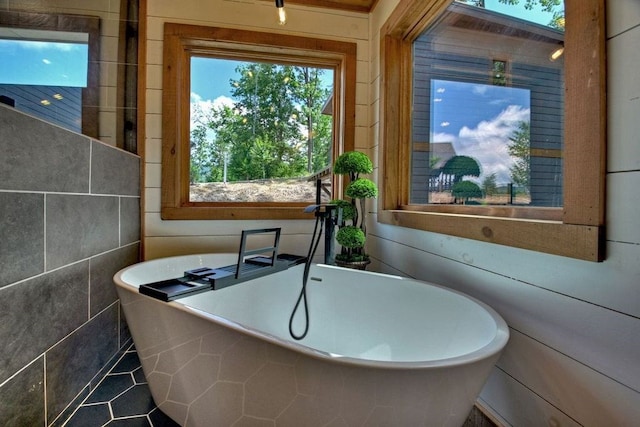 bathroom featuring a bathing tub, a wealth of natural light, and tile patterned floors