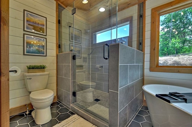 bathroom with wooden walls, tile patterned floors, toilet, and shower with separate bathtub